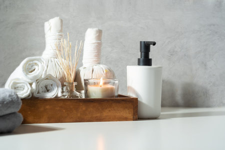 Spa, beauty treatment and wellness background with spa herbal compress balls, massage oil and burning candles on table.の写真素材