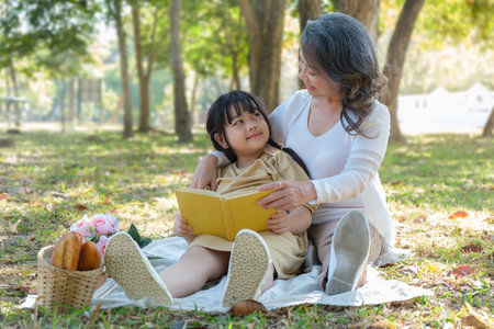 Loving mature grandmother telling story to her adorable granddaughter,  enjoy priceless time together at outdoor.の写真素材