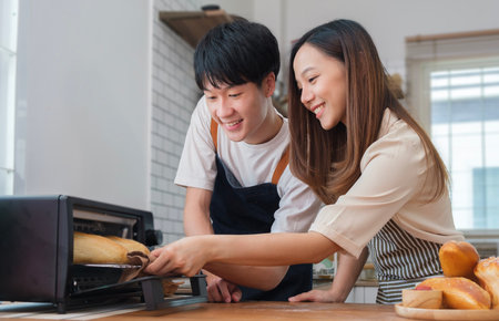 Loving couple having fun while  baking bread, preparing dinner in modern kitchen together,  enjoying leisure time at homeの写真素材