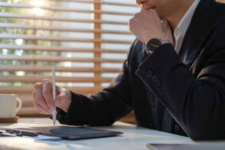 Happy businessman using stylus pen writing some information on digital tablet.の写真素材