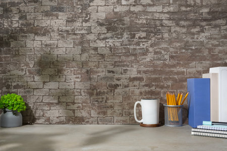 Home office desk with book, pencil holder, coffee cup and potted plant on grey table.の写真素材
