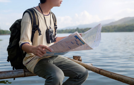 Cropped shot of male traveller with backpack and map enjoying view of nature.の写真素材