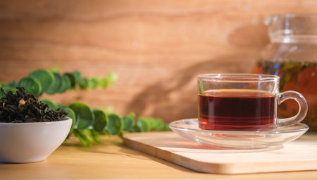 Cup of freshly brewed black tea on wooden board with dried tea leaves in background.の写真素材