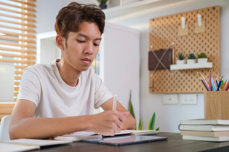 Smiling female student doing homework, working on research project online watching remote education online class o movie series on laptop  in cozy sunny living room.の写真素材