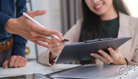 Smiling female worker explaining project plan to her colleagues during office briefing.の写真素材