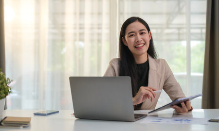 Portrait of young businesswoman in stylish suit  holding clipboard and  smiling at camera.の写真素材