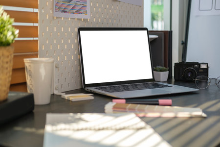 Creative designer workplace with laptop computer, color samples and camera on wooden table.の写真素材