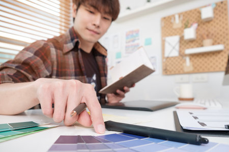 Creative Asian male ux designer choosing color samples for mobile app while working in the modern office.の写真素材