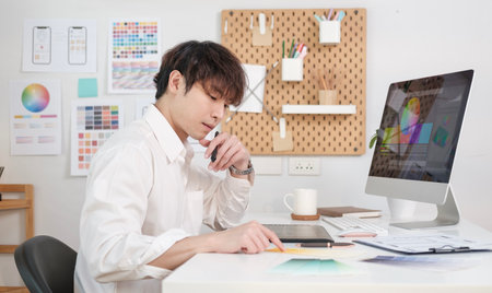 Concentrated male ux designer working with wireframe layout design mockup for responsive web content in bright modern office.の写真素材