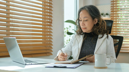 Positive mature businesswoman remote working from home on laptop laptop computer.の写真素材