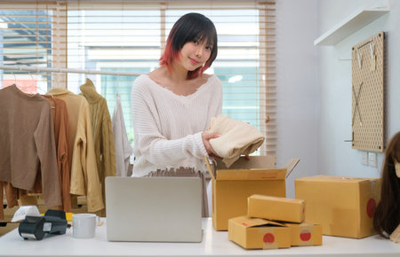 Smiling young Asian female blogger reviewing product and talking to camera during recording video on social network.の写真素材
