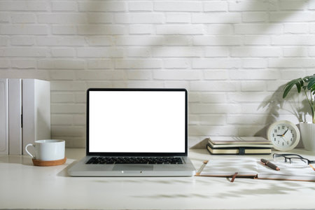 Laptop computer with empty display, picture frame and stationery on wooden working desk.の写真素材
