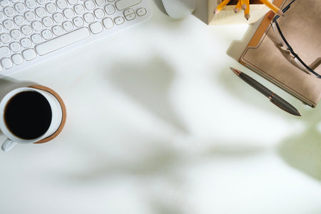 White working desk with diary, keyboard, coffee cup and glasses. Top view with copy space for your text.の写真素材
