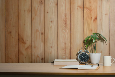 Home office desk with books, cup of coffee, pencil holder and houseplant. Copy space for your text.の写真素材