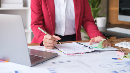 Cropped shot of female entrepreneur writing in notebook and planning for startup company or marketing strategy.の写真素材