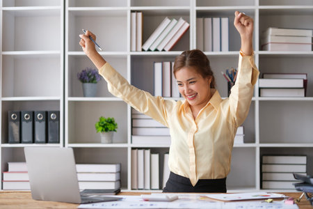 Overjoyed female employee looking at laptop screen celebrating success or getting new job opportunity.の写真素材