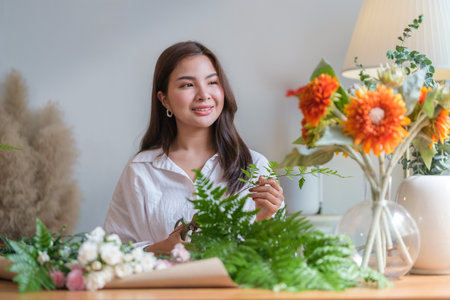 Positive female florist creating beautiful bouquet of colorful different flowers in modern interior floral shop.の写真素材