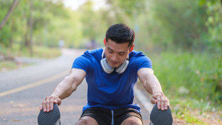 Athletic Man in sports clothes stretching his legs, warming before running in the park.