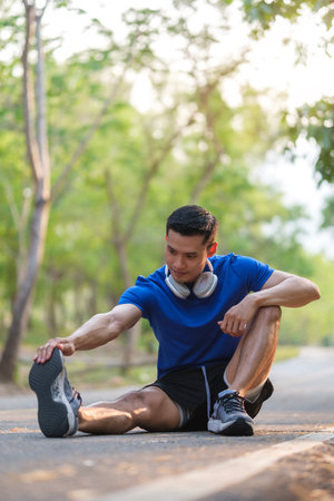 Athletic man stretching legs before jogging in morning. Physical activity, healthy lifestyle concept.の写真素材