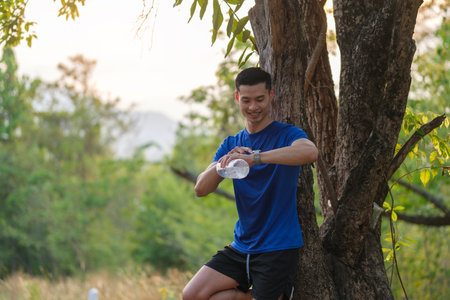 Sportsman checking his smartwatch while running in city park. Sport, exercise and fitness outdoors in nature.の写真素材