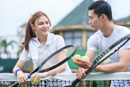 Shot of two tennis players talking during break at court on sunny day.の写真素材