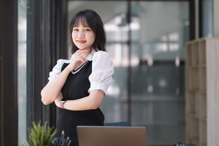 Portrait of beautiful young asian female student looking at camera while standing in university campus.の写真素材