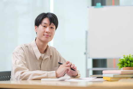 Portrait of asian male office worker sitting at desk and smiling to camera.