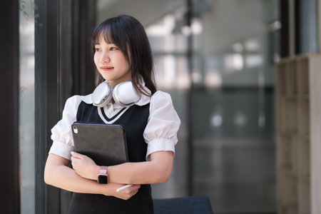 Smiling young woman college student holding digital tablet and  looking away. Education, learning,...