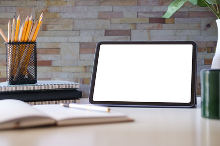 Digital tablet with empty screen on coffee cup and notepad on white office desk. Copy space for your text.の写真素材