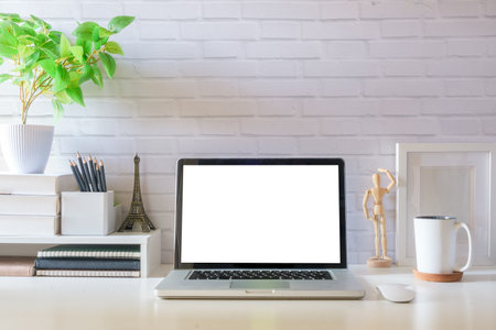 Laptop computer, coffee cup, potted plant and picture frame on creative workplace. Blank screen for your advertising text.の写真素材