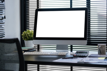 Front view of a computer with blank screen and equipment on designer or photographer workspace. Blank screen monitor for graphic display montage.の写真素材