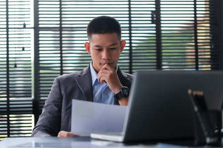 Concentrated businessman reading contract, partnership agreement and working in modern office.の写真素材
