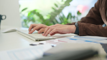 Cropped shot businesswoman working at office desk, hands typing on wireless keyboard.の写真素材