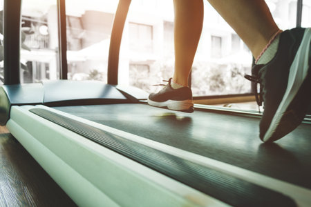Cropped image of sportswoman running on treadmill in the gym. Fitness, workout, gym exercise and...