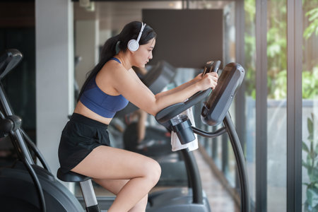 Concentrated young woman in sportswear listening to music in headphones. burning calories on spin...