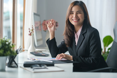 Beautiful female manager using laptop computer and working financial document at her workstation.の写真素材