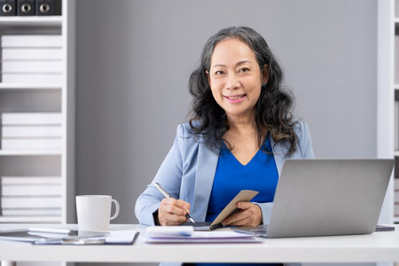 Portrait of beautiful stylish elderly businesswoman using laptop computer at office.の写真素材