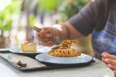 Young woman eating tasty apple pie at summer garden.の写真素材