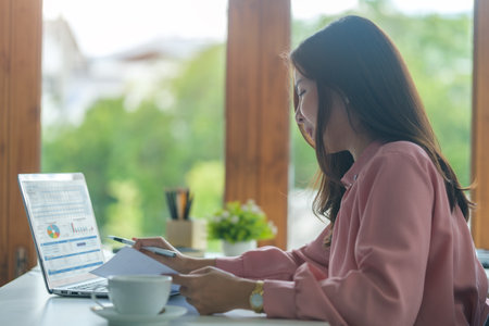 Young asian female office worker sitting in bright office and working on computer laptop.の写真素材