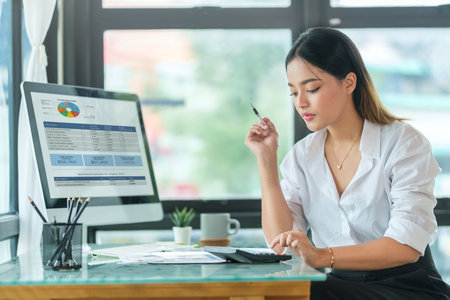 Businesswoman working with financial data sales charts on computer monitor.の写真素材