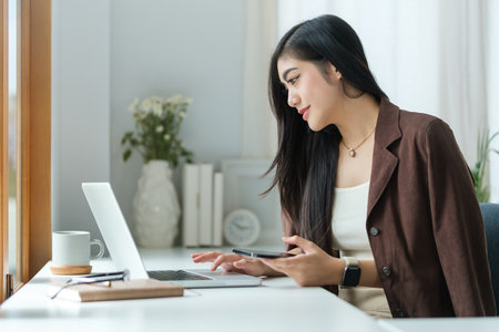 Beautiful young asian woman working with computer at bright modern office.の写真素材
