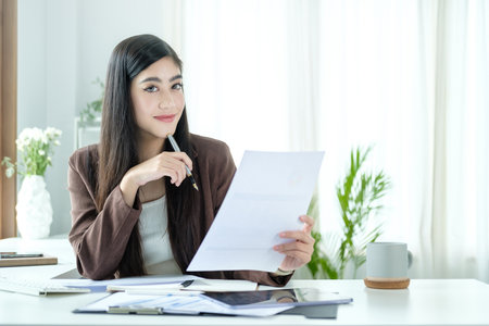 Portrait of businesswoman sitting at office desk and checking documents.の写真素材