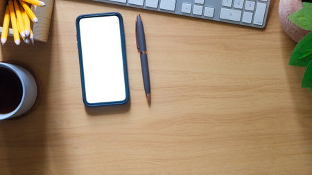Smartphone, pen, coffee cup and keyboard on wooden table. Top view with space for text.の写真素材