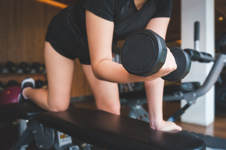Cropped image of female hands lifting dumbbells at gym. Fitness, workout, gym exercise and healthy lifestyle concept.の写真素材