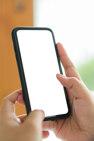 Closeup view of hands holding smartphone with blank screen and left side with empty space for your advertise or text message.の写真素材
