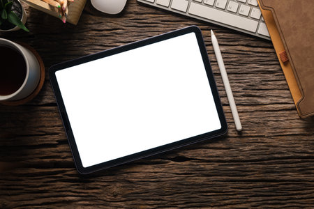 Flat lay, top view of digital tablet with blank display, laptop, notebook and coffee cup on wooden table.の写真素材