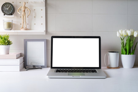 Front view laptop, coffee, notebook and houseplant on white table. Blank screen for your advertise text.の写真素材