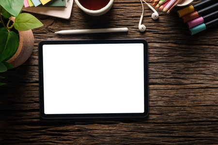 Digital tablet with blank screen, earphone and coffee cup on marble background. Top view.