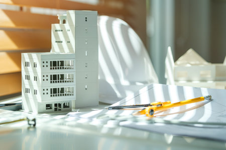 Architectural model on desk with laptop, drawing technical tools and blueprints. Architecture, building, construction and real estate business.の写真素材