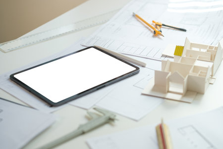 Digital tablet, architectural model of residential buildings and blueprints on table. Building, construction and real estate business.の写真素材